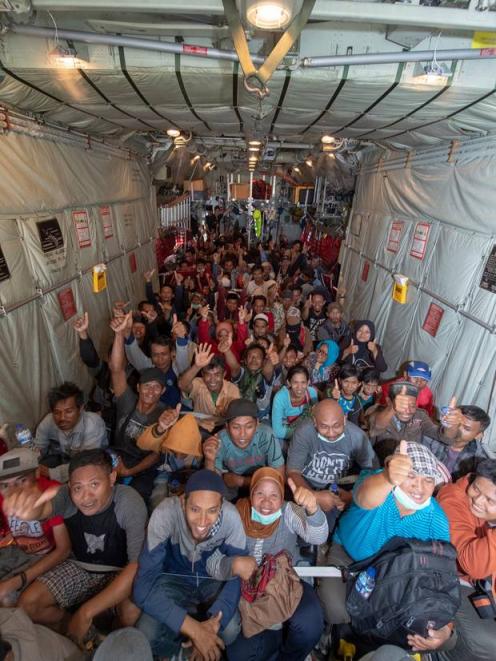 Survivors from the quake-damaged Indonesian city of Palu give a thumbs-up sign before the Royal New Zealand Air Force C-130 Hercules aircraft that evacuated them yesterday to Balikapapan. Photo: NZ Herald