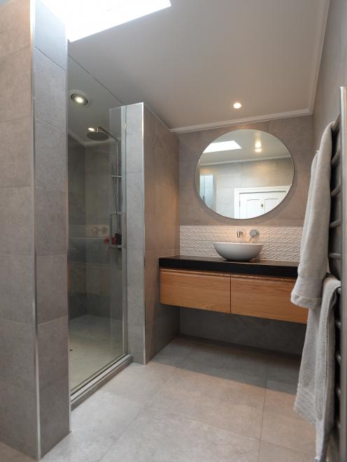 The bathrooms feature large grey tiles and oak vanities with granite tops. The white embossed...