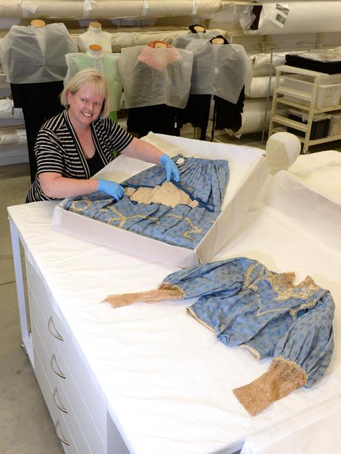Toitu Otago Settlers Museum registrar Claire Orbell examines an Edwardian blue silk wedding dress...