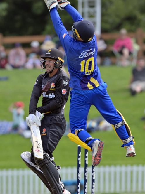 Wellington wicketkeeper Tom Blundell hits the ball while Otago wicketkeeper Ben Cox jumps in the...