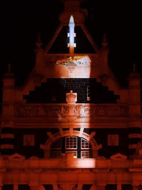 As a tribute in the wake of last Friday's Christchurch mosque attacks, an image of a burning candle is projected on to the Dunedin Railway Station last night. Photo: Peter McIntosh