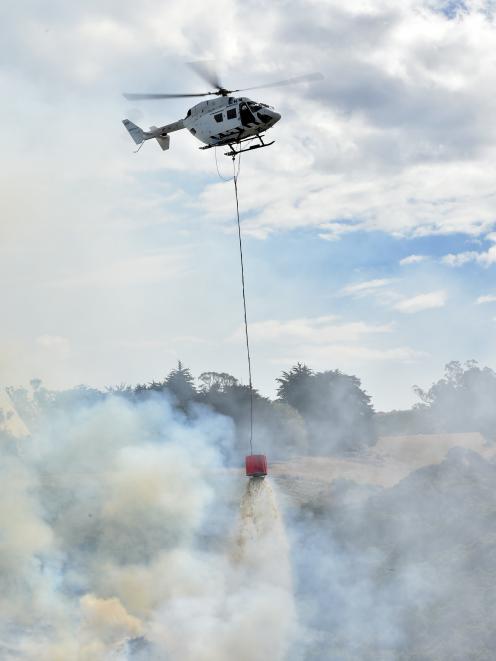 A helicopter douses a grass and gorse fire near Taieri Mouth yesterday. Photo: Gregor Richardson