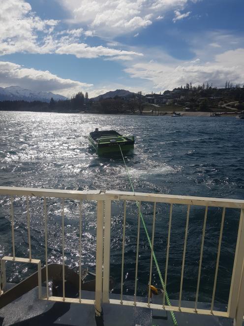 The houseboat Lady Pembroke is towed back to its moorings on Lake Wanaka by a jet-boat skippered...