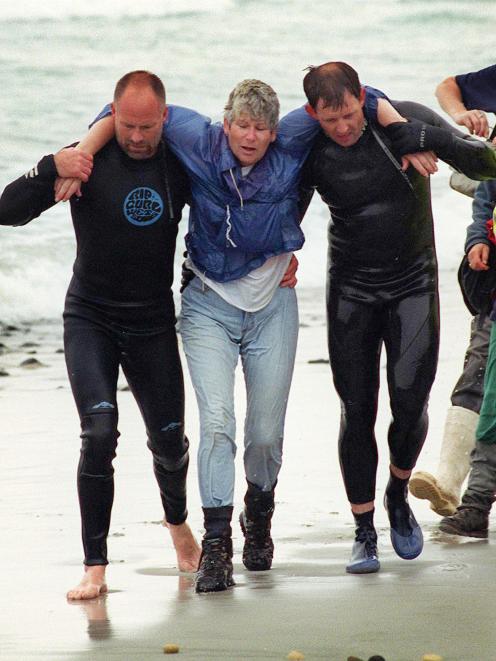 Margaret Dodds is helped to shore by rescuers Neil Price (left) and Senior Sergeant Brian Benn....