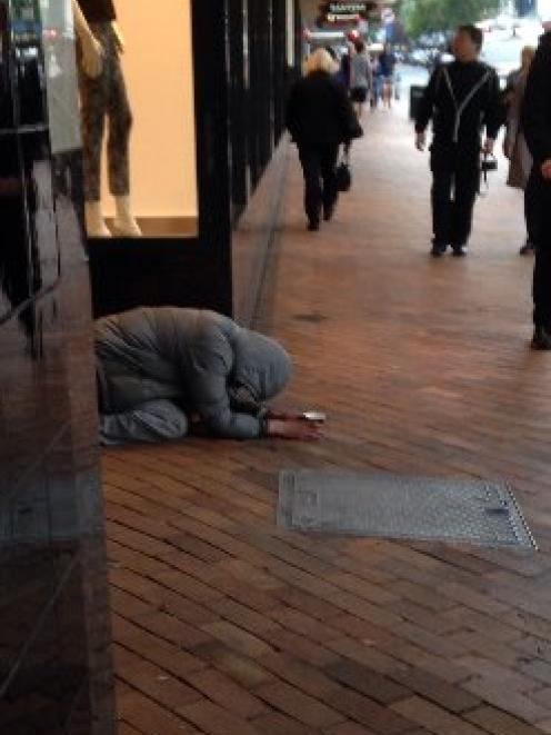 'Samuel' crouches, begging, behind an empty coffee cup in George St on Monday.  Photo by The Star.