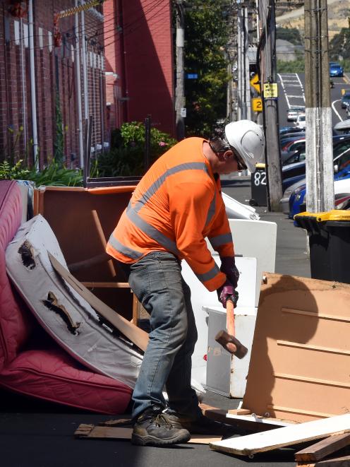 A contractor breaks up discarded furniture before removing it on Dundas St, in Dunedin’s student quarter, yesterday. Photo: Stephen Jaquiery