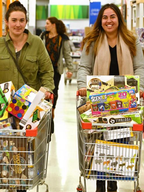 Vickie Schroder (left) and Grace Patu, both staff members at the charitable Mount Cargill Trust, fill their trolleys with games, to give to those living in its eight residential homes for people with intellectual and learning disabilities to help fill in 