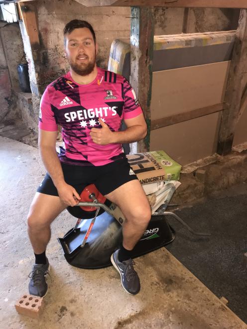 Highlanders prop Ayden Johnstone on the wheelbarrow piled high with cement and other weights he...