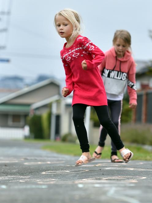 Lexi (front, 6), and Lara Lowe (8) try out a hopscotch game on Bayview Rd. Photo: Peter McIntosh