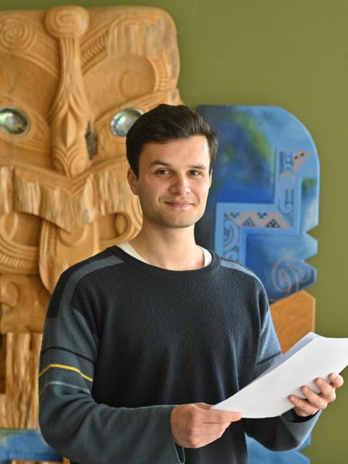 Law and arts student Jacobi Kohu-Morris holds his speech notes in front of a carving of Ko Tane...
