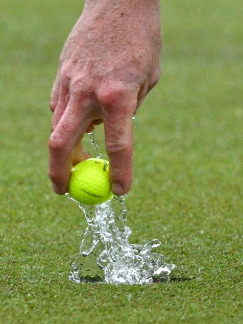 Leith Campion retrieves his ball from the hole during a rain-soaked semifinal of the Otago...