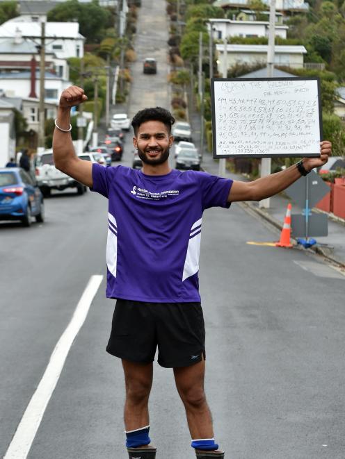 Dairy farmer Harjinder Singh Chander holds a white board recording his success at running up and...