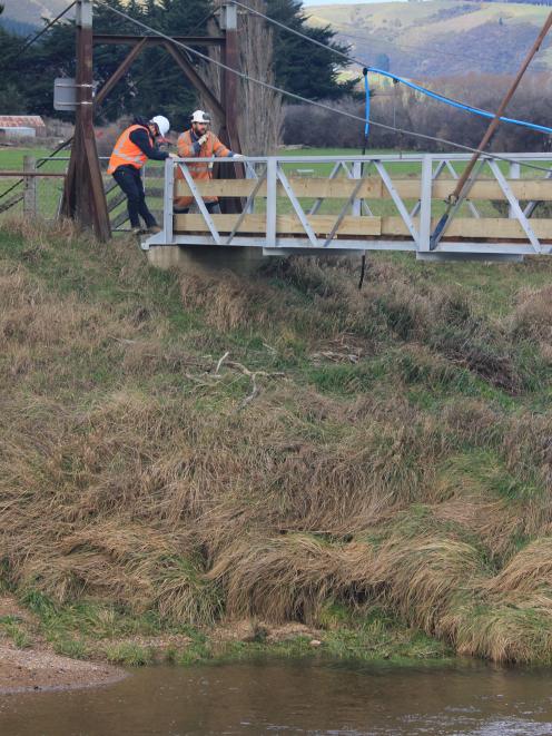 Construction workers manoeuvre a new foot bridge into place across the Silver Stream in Gladfield...