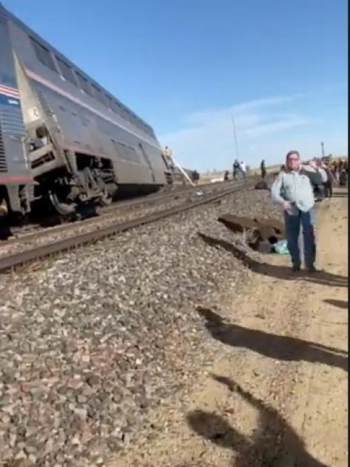 People wait at the side of train tracks at the scene of an Amtrak train derailment near Havre,...