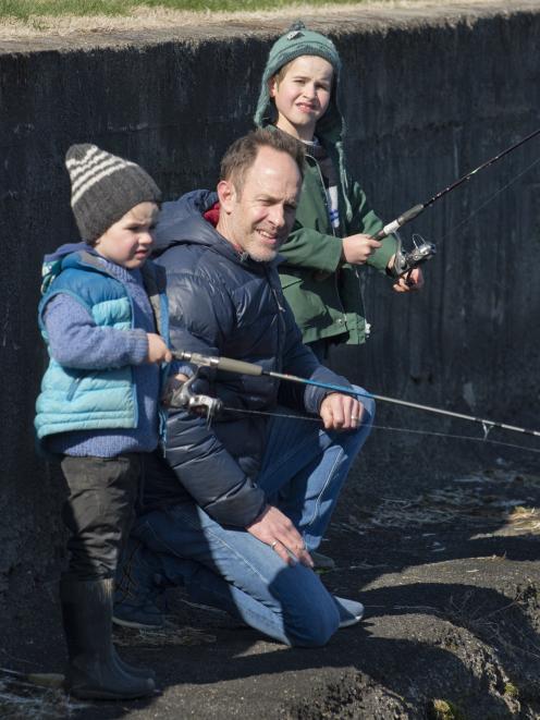 The Dukes family (from left) Claude (4), Breton and Hector (6) wait patiently to reel in a fish....