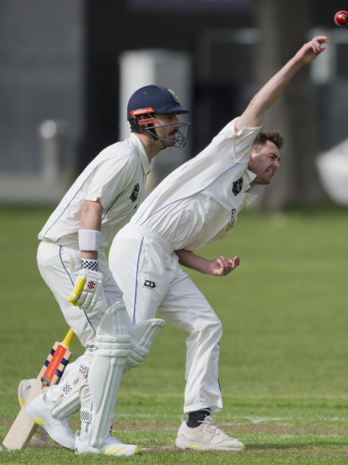 Otago seamer Travis Muller sends down a delivery while senior batsman Hamish Rutherford waits at...