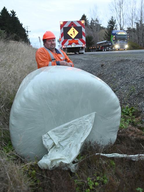 Traffic management specialist Stuart Hewson with a bale of baleage which fell from a truck on...