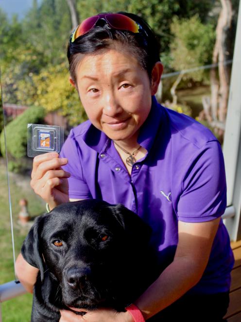 Tama Sasaki with her dog 007 shows the SD card she found 10 years ago filled with special family...