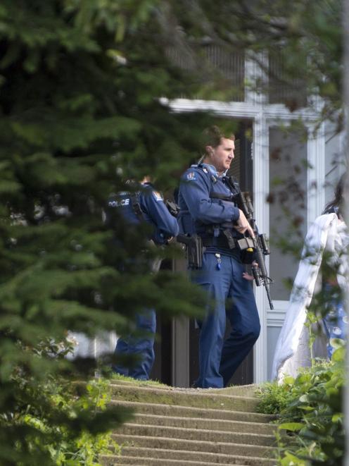 Armed police stand at the door at an address where a grievous assault occurred this morning on...