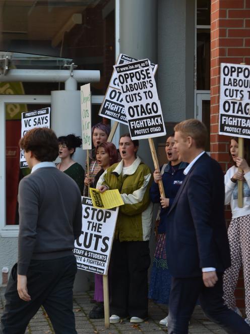 Prime Minister Hon Chris Hipkins walks past protesters after speaking at the Otago University...