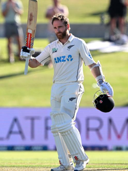 Kane Williamson raises his bat after scoring a century during day one of the first test against...