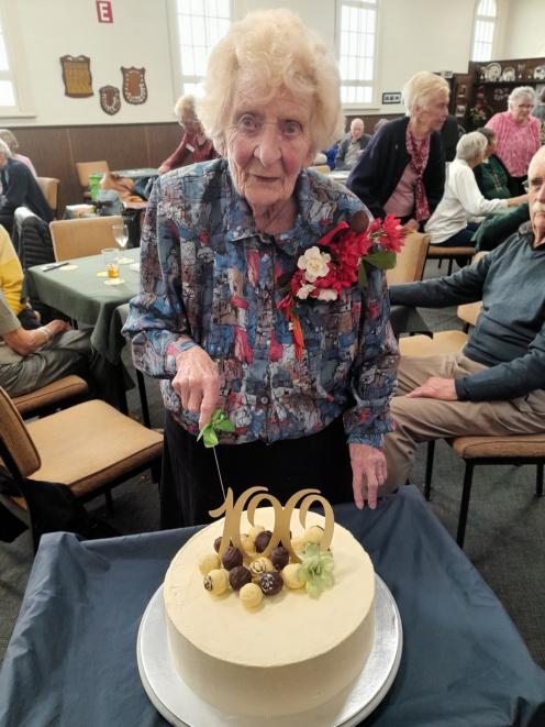 Eileen Fake cuts her 100th birthday party cake, a "House & Garden" model made by Oamaru Bridge...