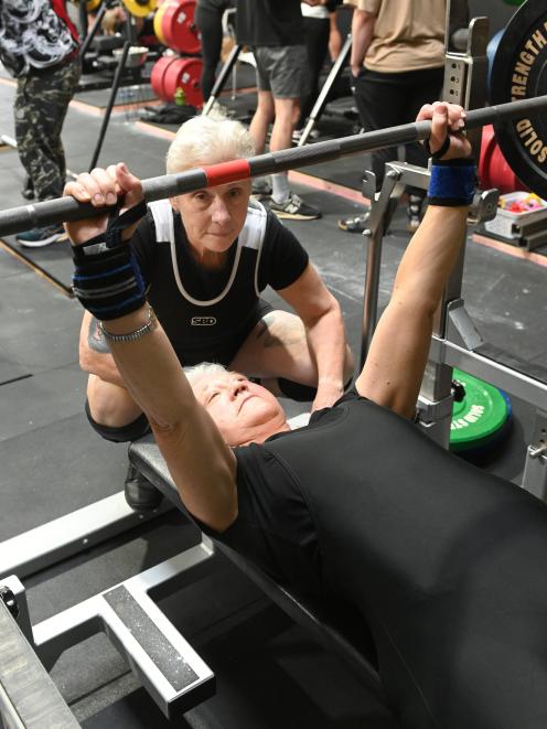 Nicola Atwool (70) warms up for her first weightlifting competition, spotted by partner Lesley...