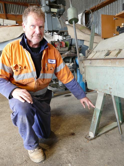 Mr Duffy points to a high floodwater mark in his machine shop.