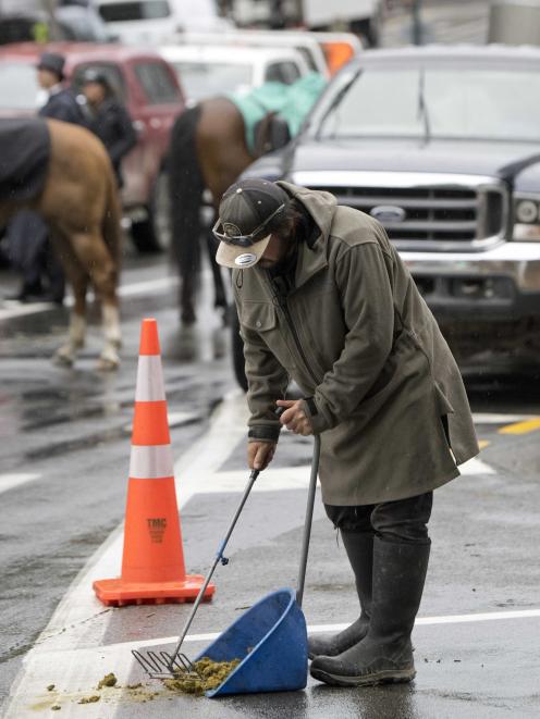 A crew member shovels up horse dung on the Princes St set at dawn.