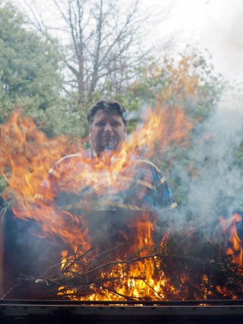 Dr Tim Curran assess the flammability of gorse on his barbecue. Photo: David Hollander 
