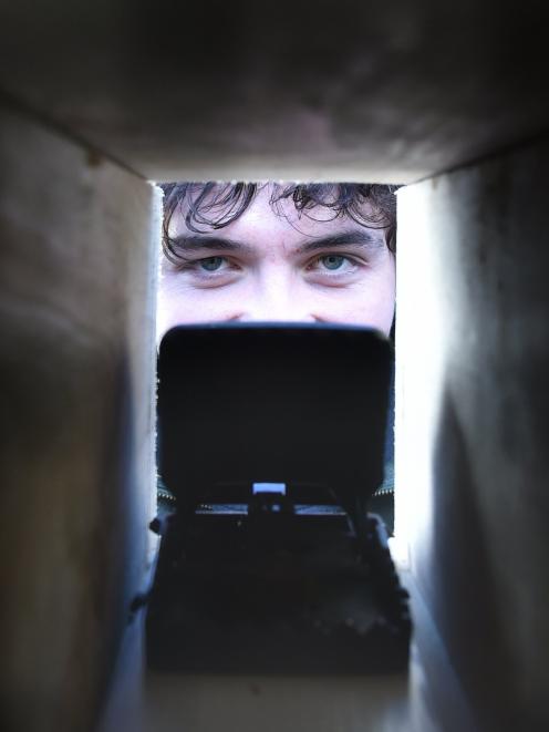 University of Otago student Bradley Thomas peers down a peanut butter-loaded rat trap. PHOTO:...