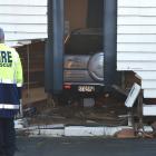 A firefighter inspects a Honda CR-V driven through a wall of the gymnasium at Arai Te Uru Whare...