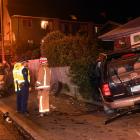 Emergency services attend a crash involving an SUV, a parked van and a brick house in North...