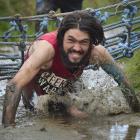 Mud, Sweat and Tears men’s 10km winner Jonah Smith, of Dunedin, crawls through a muddy ditch....