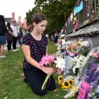 Eloise Piper lays flowers at a makeshift memorial near the Arts Centre on Saturday afternoon.
