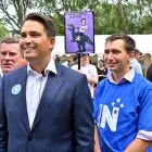 Protester Sam Sharpe holds up a sign behind (from left) National List MP Michael Woodhouse,...