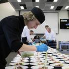 Young chef Caleb McCall concentrates putting a pickled cucumber on the beef plate, one of the six...