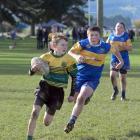 Green Island player Mason Bond (11) runs to the try line with Charlie Craig (12), of Taieri,...