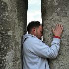 A man touches the stones during spring equinox celebrations at Stonehenge stone circle, near...