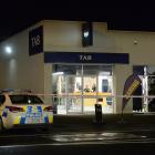 Armed police guard the scene at the TAB on Hillside Rd on Saturday after a man with a gun made...