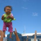 Nine-month-old Maya Rose Satake giggles with glee as she is tossed into the air by her father,...