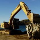 A digger moves a large boulder into place during repair work to the Aramoana mole. Photo by...