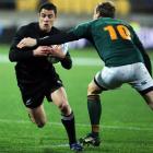 All Blacks first five-eighth Dan Carter runs through the tackle of his South African counterpart...