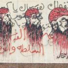 A woman walks in front of a mural of depicting Muslims that reads 'Power and wealth to the people...