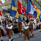Flag-bearing schoolchildren march in the Sechselauten festival children's parade. Other children...