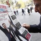A man studies a newspaper displayed on a stand, in Tbilisi, with images of Georgian Prime...