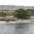 Workers clear a path for the dredge to be launched into the Clutha River, near Coal Creek. Photo...