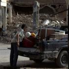 A boy loads a truck with the remains from his shop in Deir al-Zor after it was damaged by what...