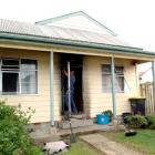 A builder repairs the door of a house at Ocean Grove, Dunedin, which was the target of arson...