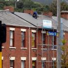 A building contractor replaces a slate tile roof with corrugated iron on one of the historic...